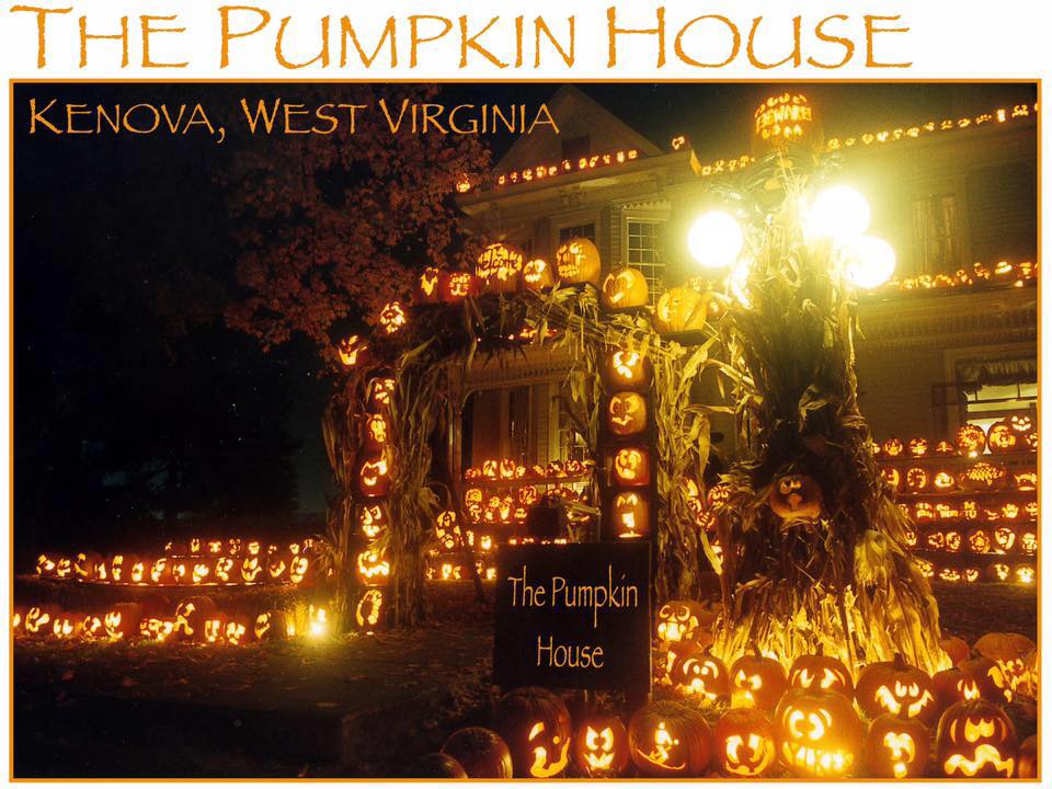 Night view of the Pumpkin House porch covered in glowing jack-o'-lanterns with its sign